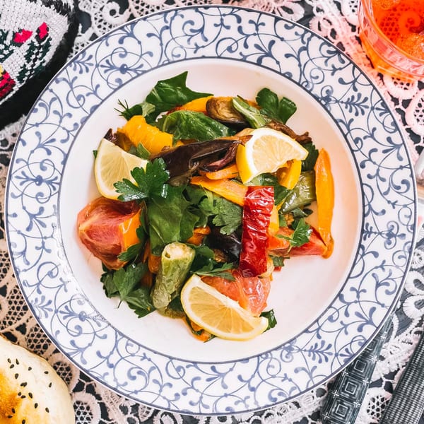 A vibrant Mediterranean roasted vegetable salad with bell peppers, eggplant, and lemon slices.