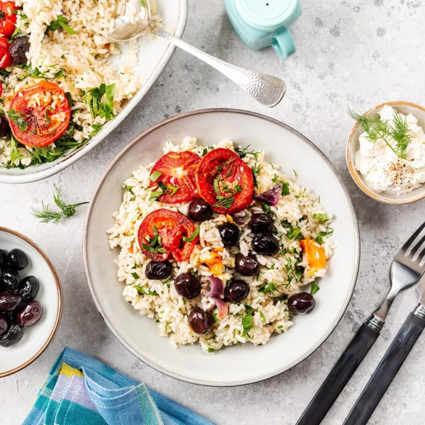 Mediterranean rice dish with roasted tomatoes, black olives, and herbs, served with a side of feta.